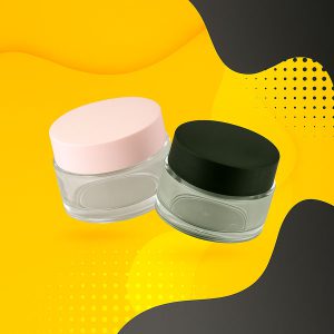 تصویر ظروف جار شیشه‌ای با درب مشکی و صورتی، مناسب برای بسته‌بندی کرم‌ها و محصولات آرایشی بهداشتی
