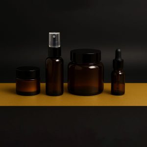 تصویری از ظروف تخصصی آرایشی شامل پوکه ژل ابرو و شیشه کرم پودر لوکس روی پس‌زمینه مشکی و طلایی با نورپردازی استودیویی